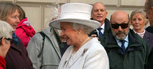 The Queen in a white coat and hat speaks to the group from the Dog Rose Trust after she had opened the tactile interpretation panel in Parliament Square.